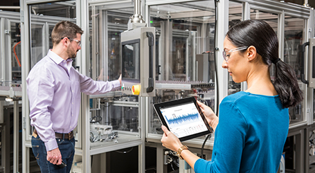 Two employees looking at machine insights on tablet