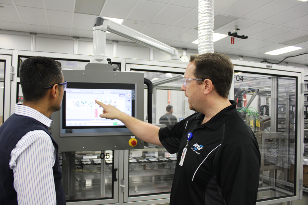 Due operatori in piedi davanti a uno schermo operatore su una macchina, che esaminano le prestazioni della macchinaAssistenza in loco