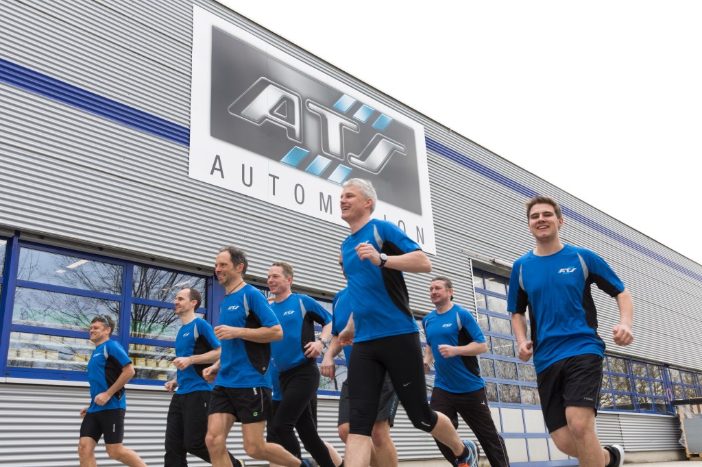 Un gruppo di dipendenti corre davanti a un edificio di ATS Automation nell'ambito di un evento di beneficenzaGrande