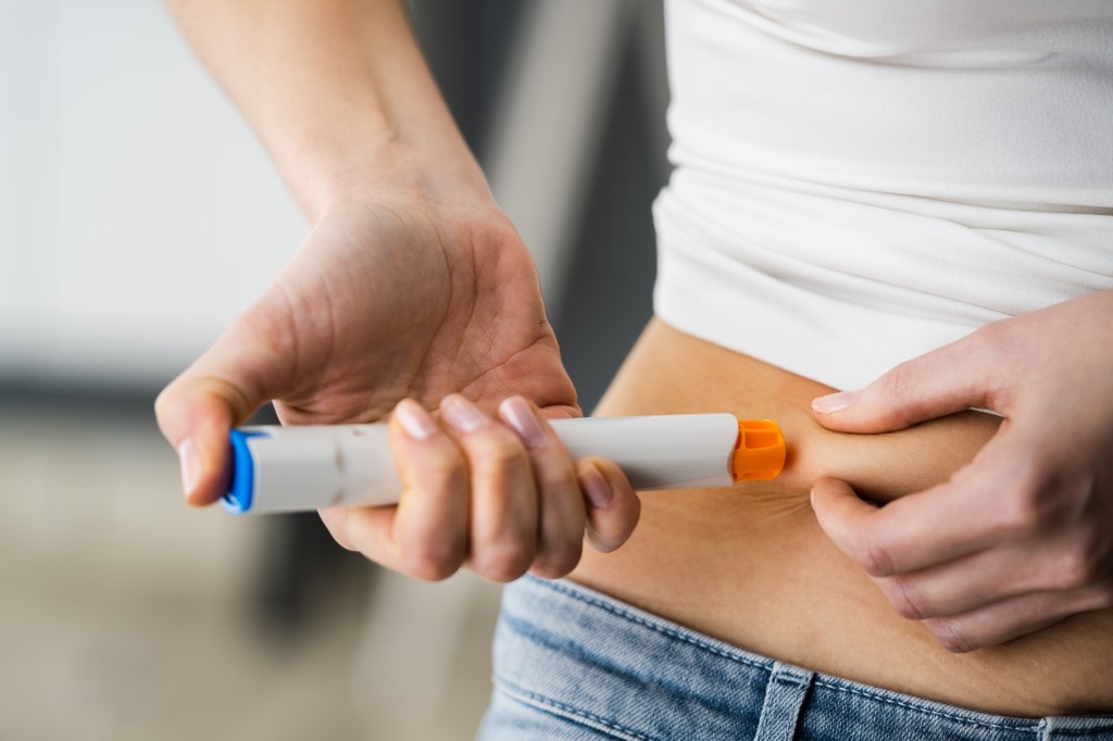 Eine Frau, die sich selbst eine Spritze in den Bauch verabreicht