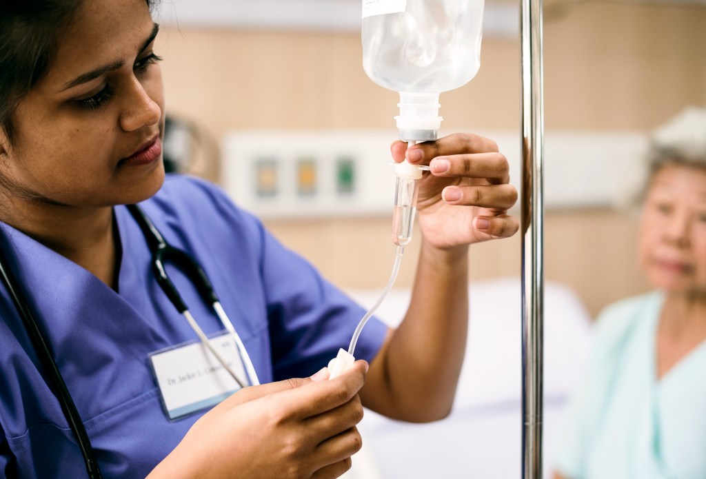 Eine Pflegekraft, die ein Infusionsschlauchset anpasst